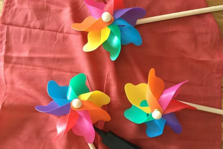 Mehrere bunte Windrädchen liegen auf einem roten Stoff.