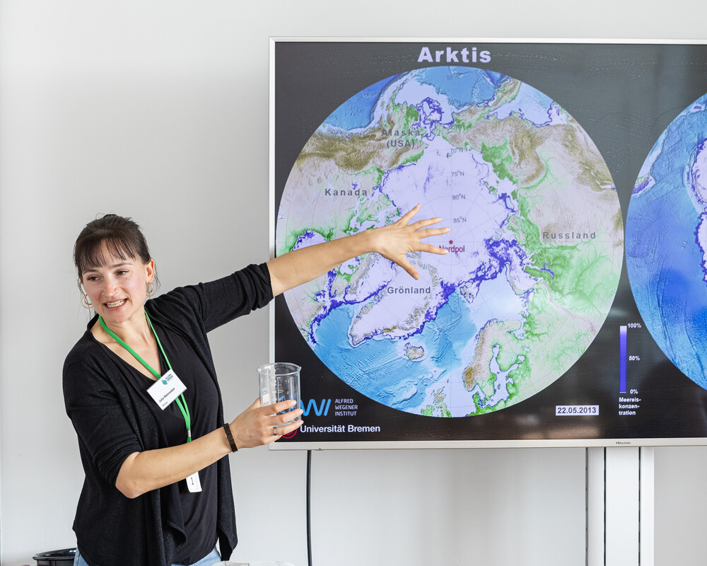 Bildungsmitarbeiterin zeigt an Schaubild das Eisschild in der Arktis.