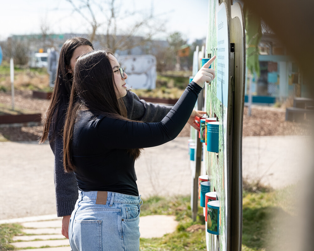 Schülerinnen bei einer schauen sich Ausstellungsstation im Außenbereich der KLIMA ARENA an.