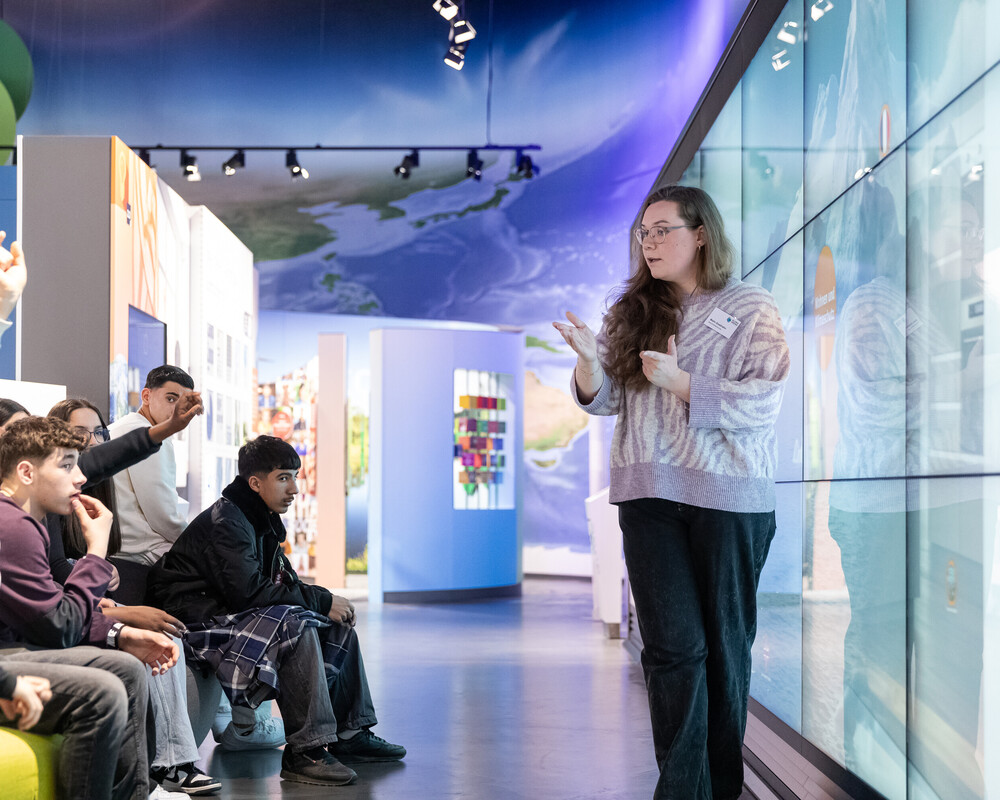 Besucherbetreuerin mit Schulklasse bei einer Führung durch die Ausstellung.