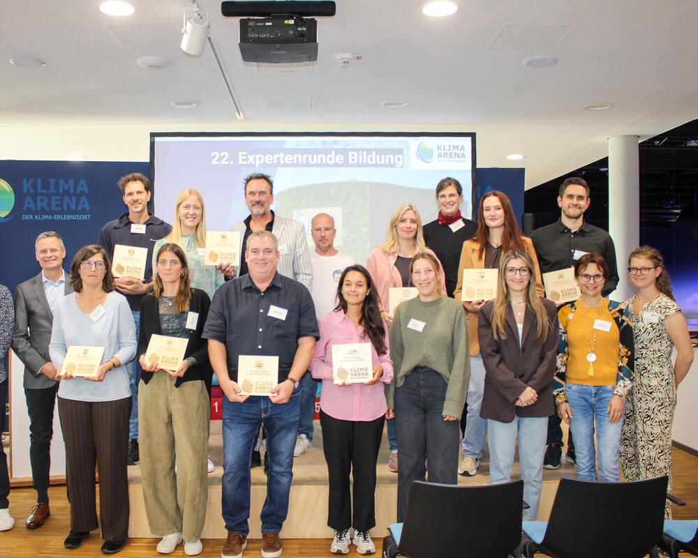 Lehrkräfte aus den ersten Partnerschulen präsentieren ihre KLIMA ARENA Schulplakette.